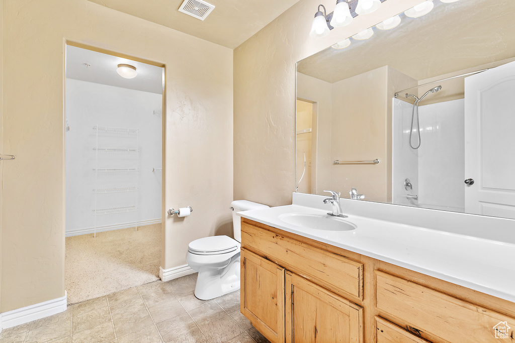 Bathroom featuring toilet, vanity, baseboards, and a shower