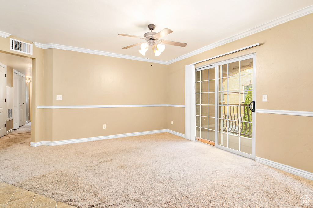 Carpeted empty room featuring a ceiling fan, ornamental molding, and baseboards
