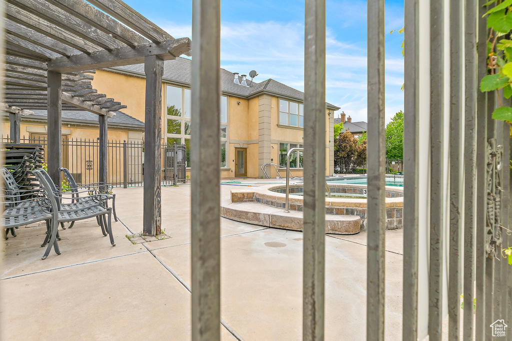 View of patio with an in-ground hot tub, a pergola, and fence