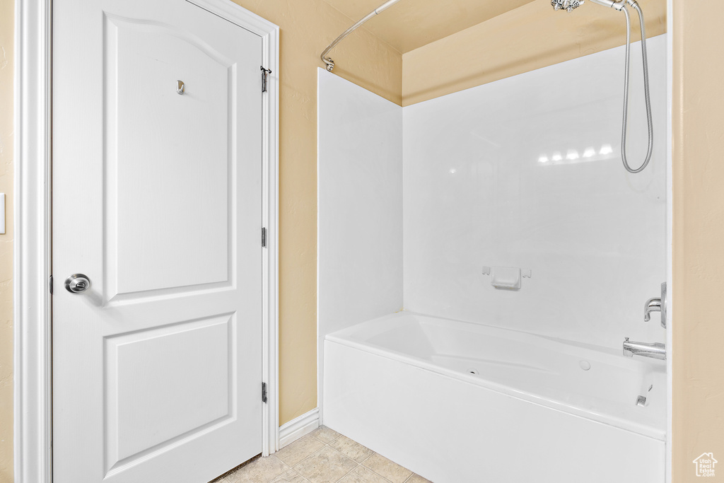 Bathroom featuring tub / shower combination, baseboards, and tile patterned floors