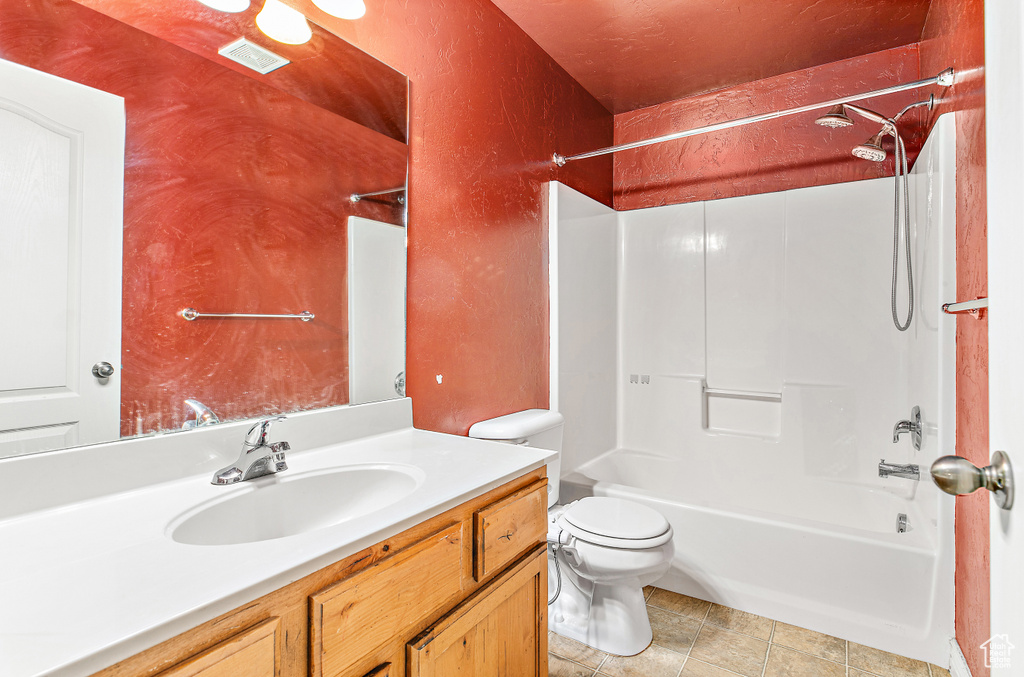Bathroom with toilet, vanity, shower / washtub combination, and a textured wall