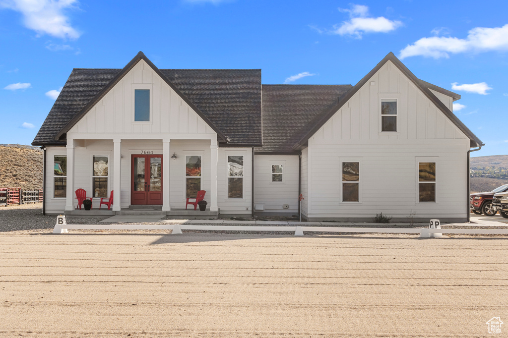 View of front of home featuring board and batten siding, french doors, and roof with shingles