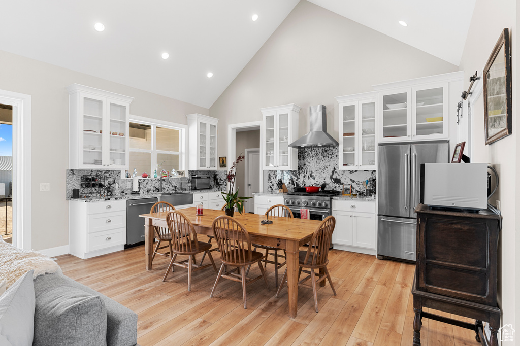 Dining area with high vaulted ceiling, light wood-style flooring, and recessed lighting