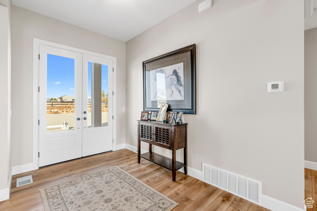 Foyer featuring french doors, light wood finished floors, and baseboards