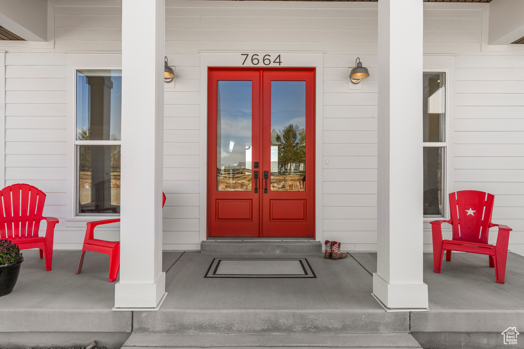 View of exterior entry featuring french doors and covered porch