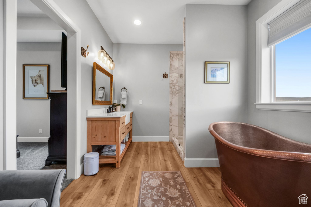Bathroom with vanity, a soaking tub, wood finished floors, a shower, and recessed lighting