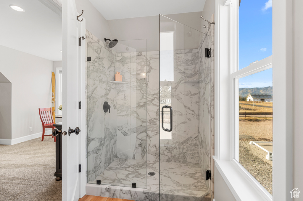 Full bath with a marble finish shower and baseboards