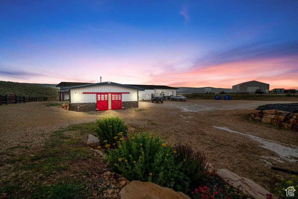 View of front of house featuring a garage, driveway, an outdoor structure, and an outbuilding