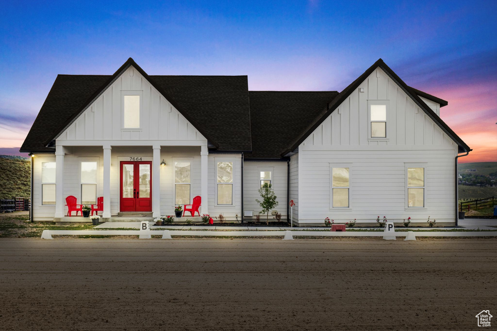 Modern farmhouse featuring board and batten siding, french doors, and roof with shingles