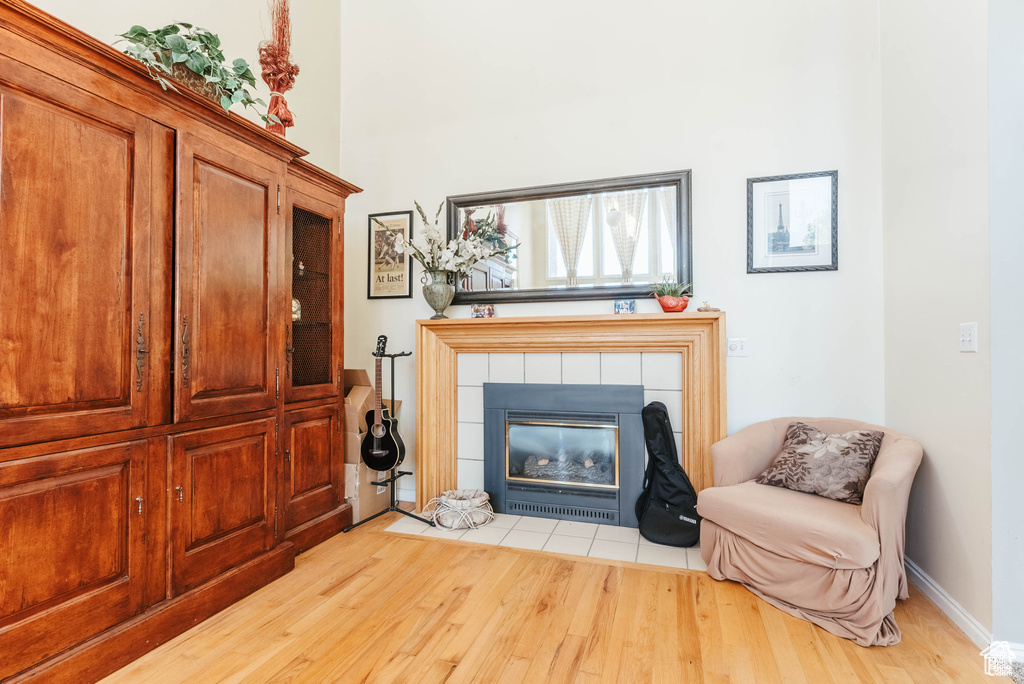 Living area with wood finished floors, a fireplace, a towering ceiling, and baseboards