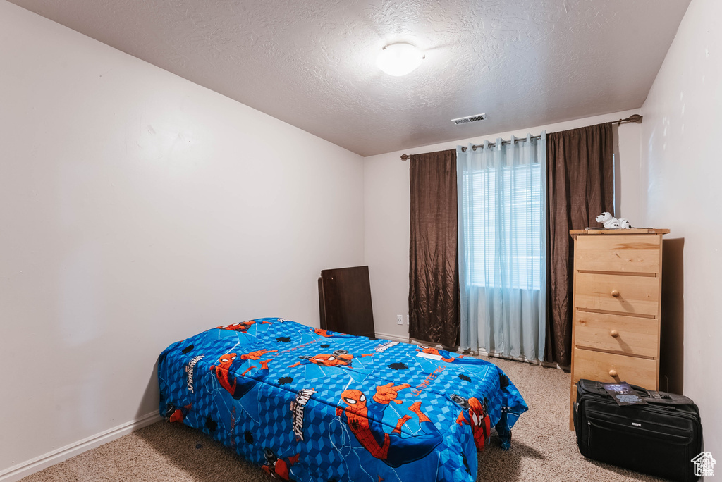 Carpeted bedroom featuring a textured ceiling and baseboards