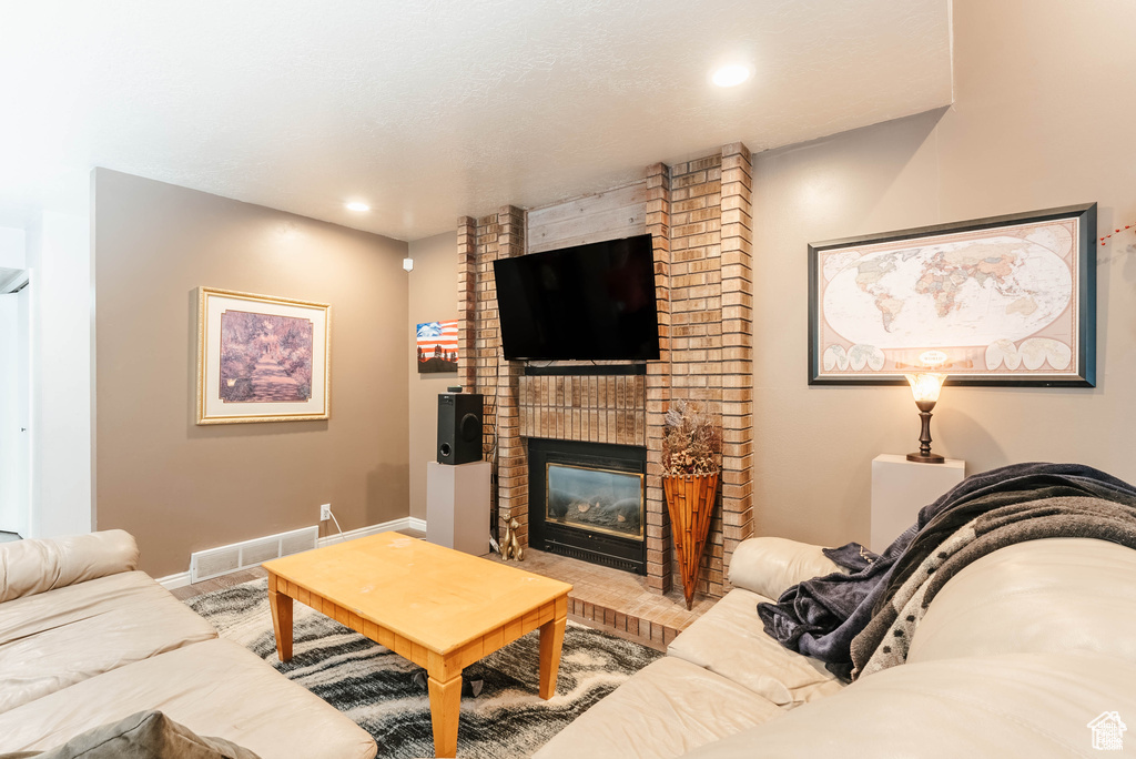 Living area with a fireplace, baseboards, recessed lighting, and wood finished floors