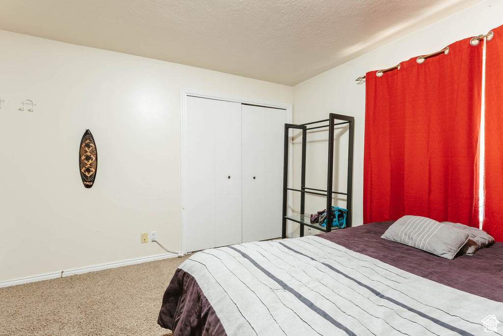 Carpeted bedroom with a closet, baseboards, and a textured ceiling