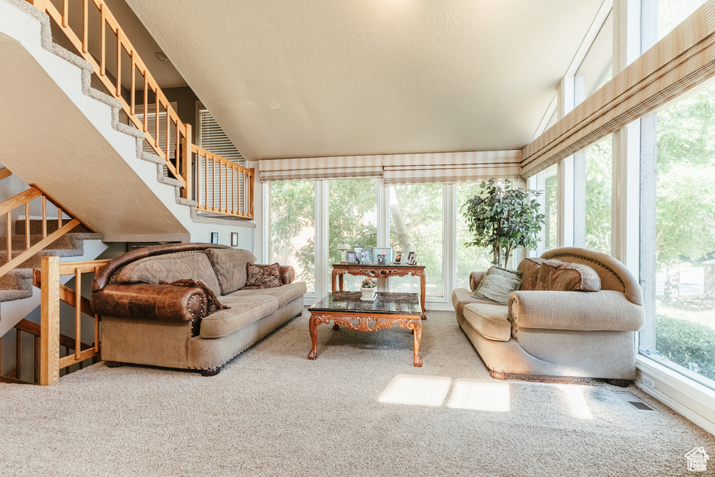 Carpeted living area featuring stairway and vaulted ceiling