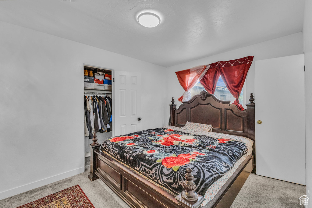 Bedroom featuring a closet, light colored carpet, and baseboards