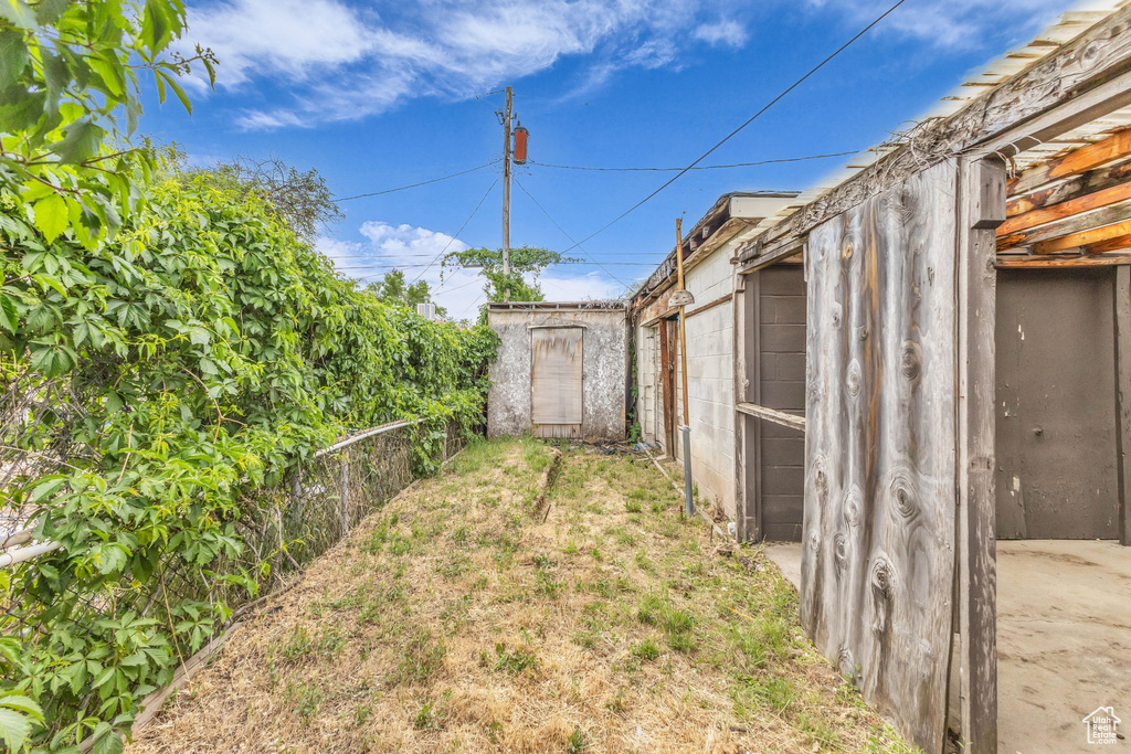 View of yard featuring fence, a shed, and an outbuilding