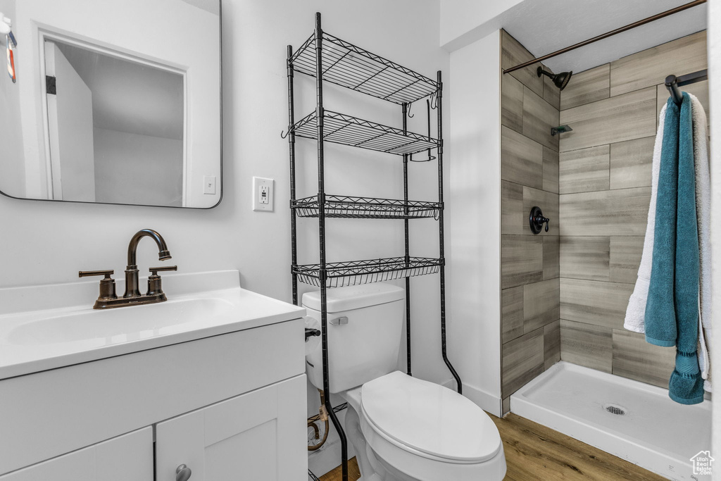 Full bath with a shower stall, vanity, toilet, and wood finished floors