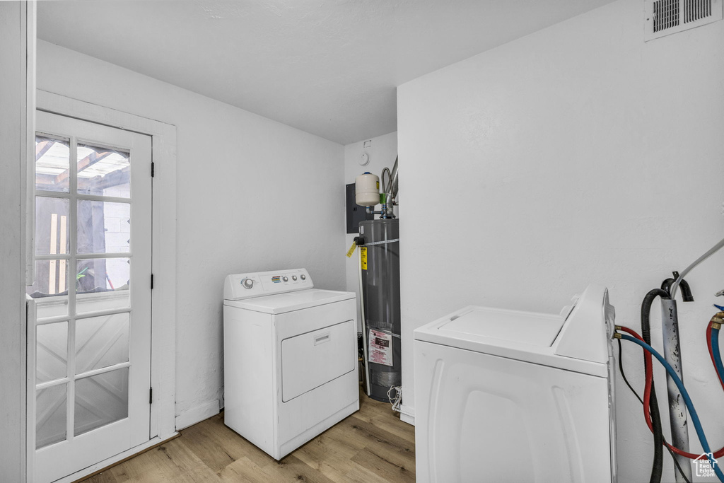 Laundry area featuring separate washer and dryer, light wood-style flooring, and water heater