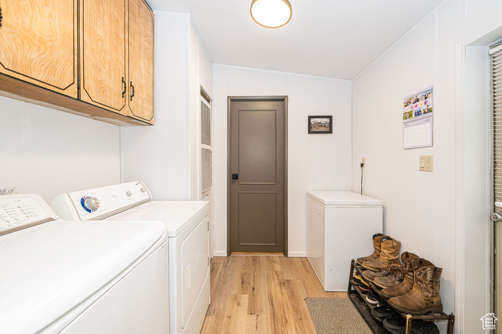 Laundry area with cabinet space, light wood-style floors, and washer and dryer