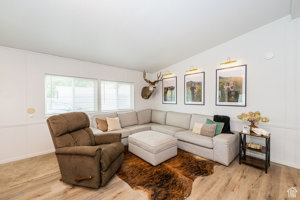 Living room featuring a decorative wall, light wood-style flooring, and vaulted ceiling