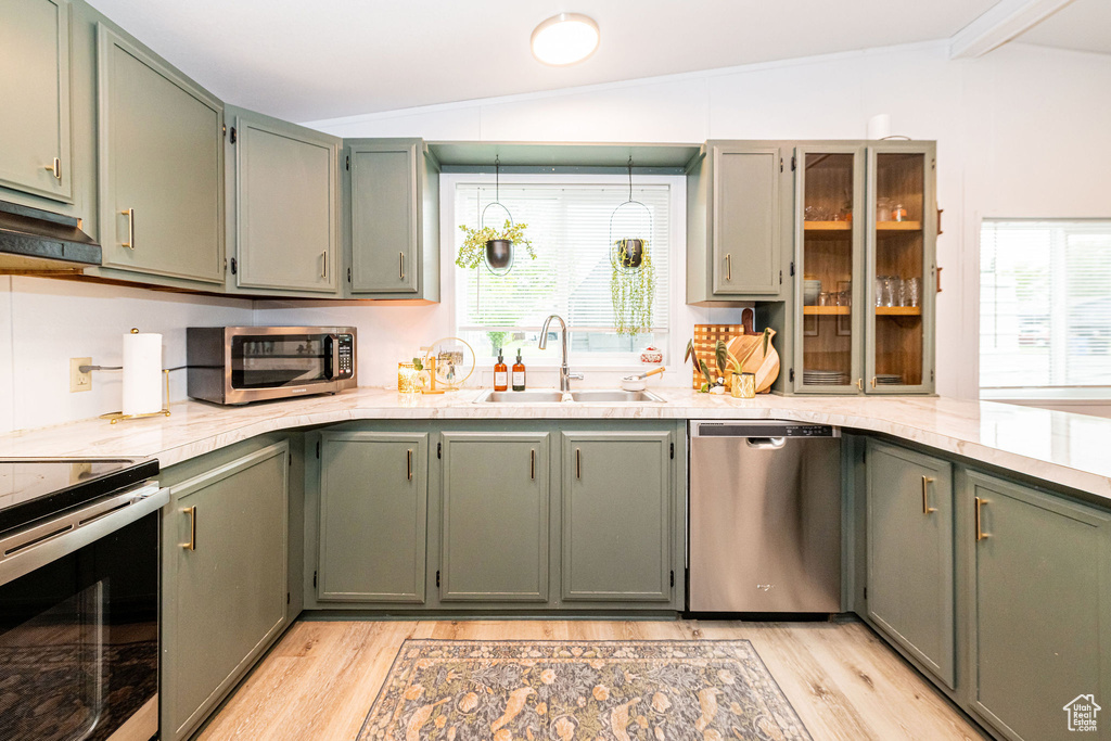 Kitchen featuring stainless steel appliances, a sink, light wood-style floors, under cabinet range hood, and healthy amount of natural light