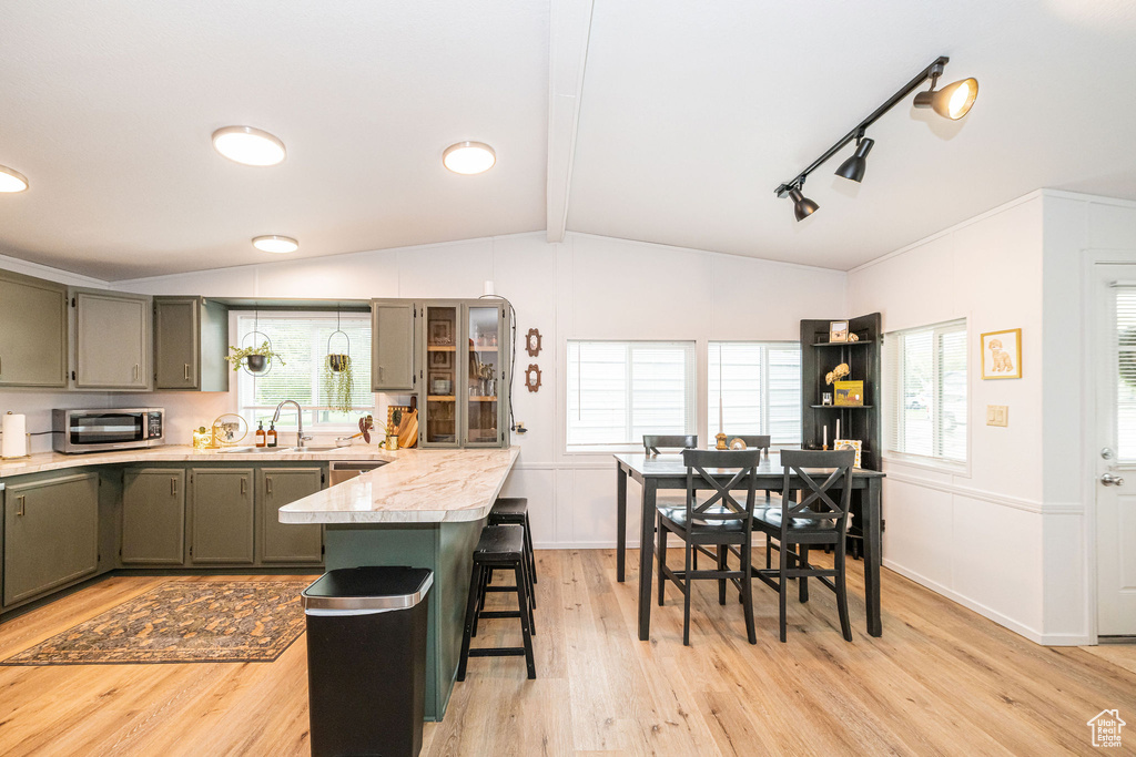 Kitchen featuring a kitchen bar, light wood-style flooring, a sink, light countertops, and gray cabinets