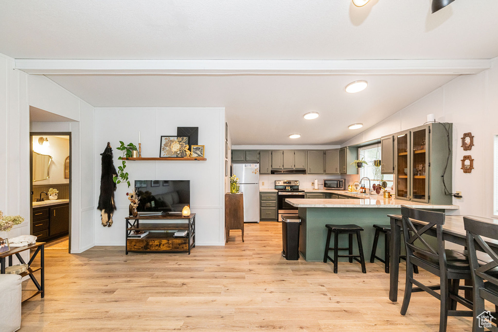 Kitchen with appliances with stainless steel finishes, a peninsula, a sink, light countertops, and light wood-style floors
