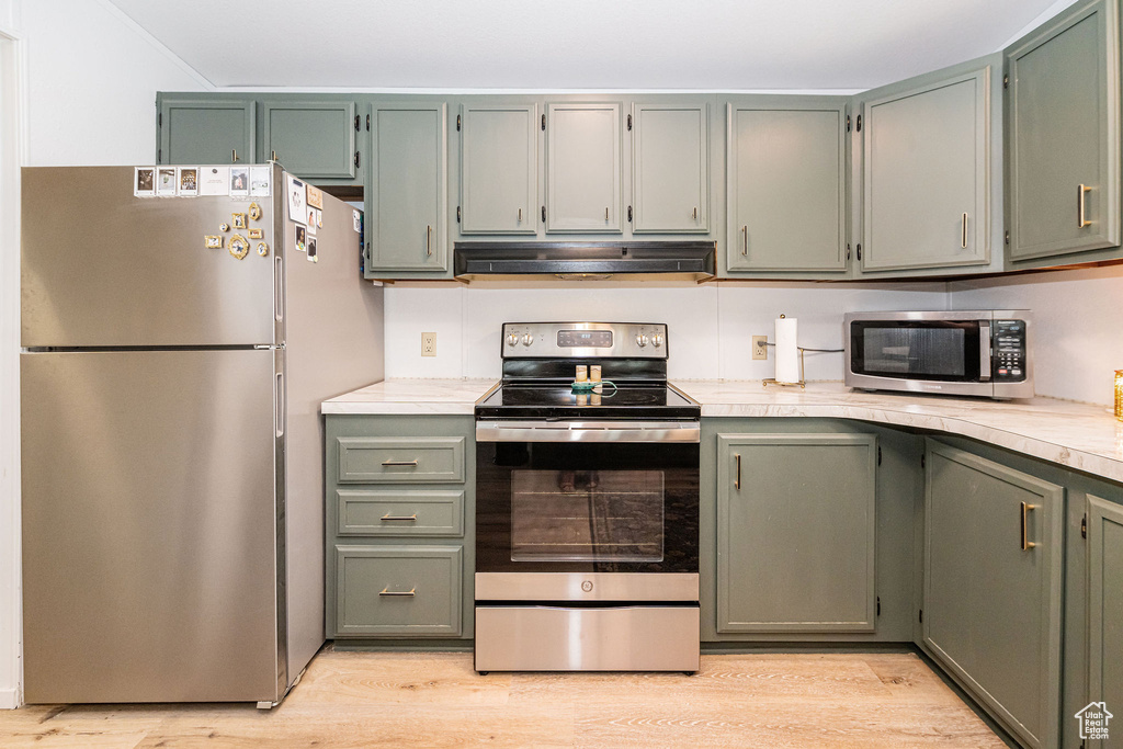 Kitchen featuring stainless steel appliances, extractor fan, light countertops, and light wood-style floors