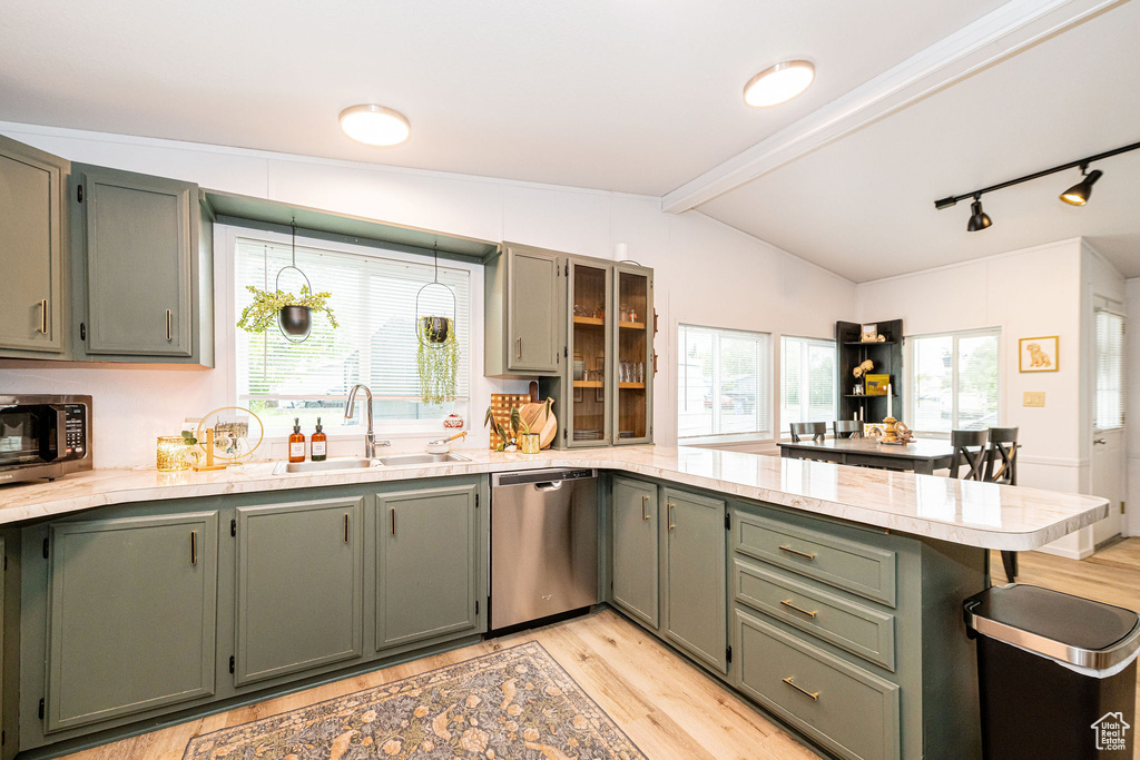 Kitchen with stainless steel appliances, a peninsula, light countertops, light wood-style floors, and rail lighting