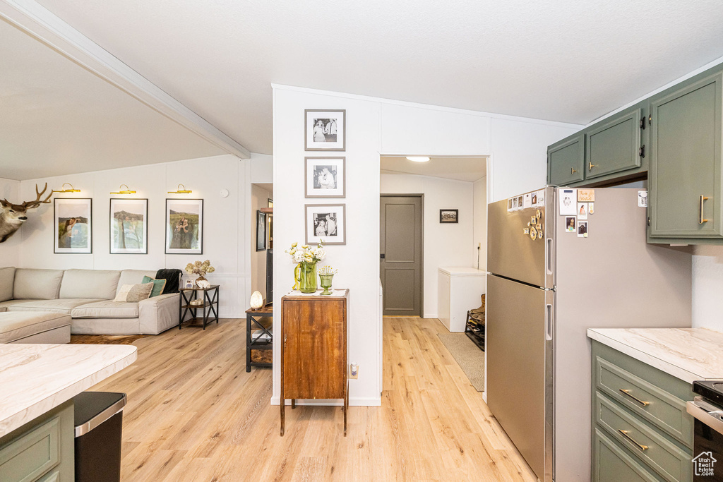 Kitchen with green cabinets, light wood-style flooring, light countertops, open floor plan, and freestanding refrigerator