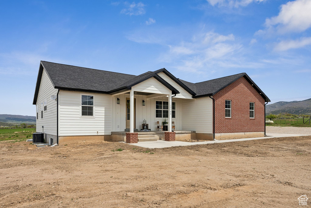 View of front facade with a porch, a mountain view, and a shingled roof