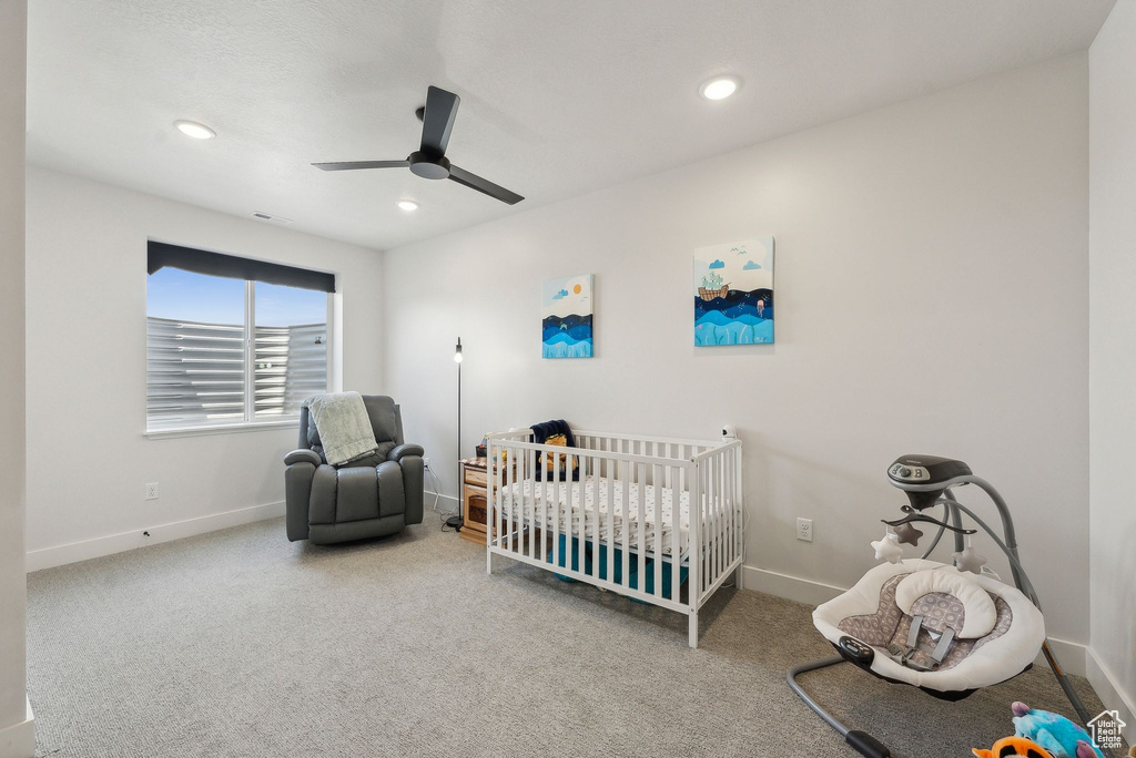 Carpeted bedroom featuring recessed lighting, ceiling fan, baseboards, and a nursery area