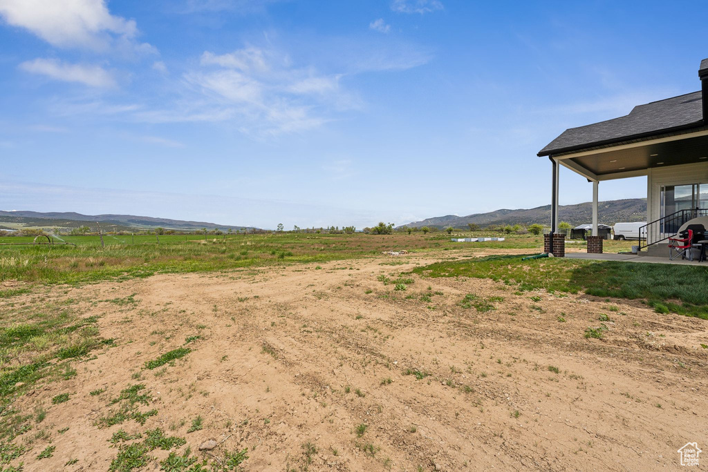 View of yard with a mountain view, a patio, and a rural view