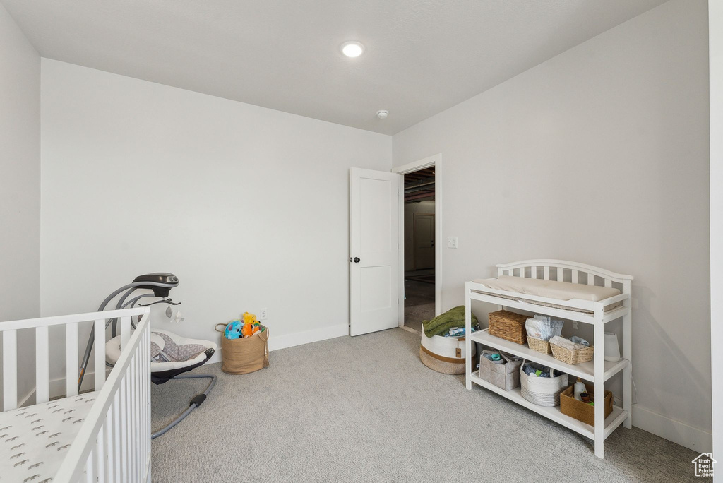 Carpeted bedroom with baseboards and a crib