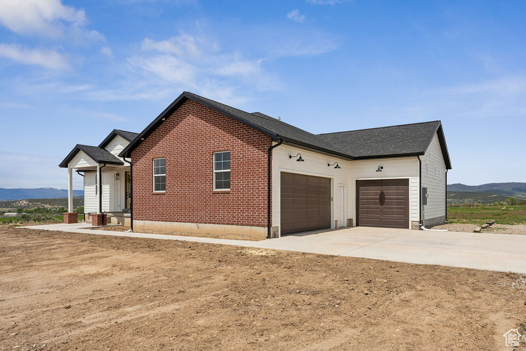 View of side of property featuring a garage, a mountain view, concrete driveway, and brick siding