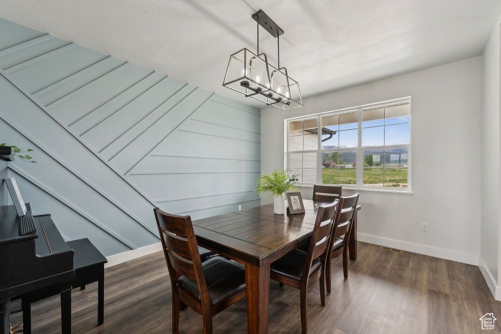 Dining area with a chandelier, baseboards, and dark wood-type flooring
