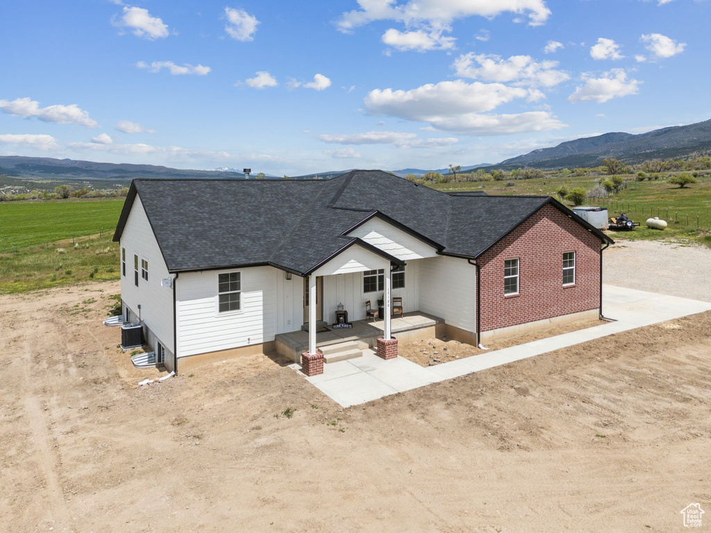 Single story home featuring a mountain view, a shingled roof, cooling unit, and brick siding