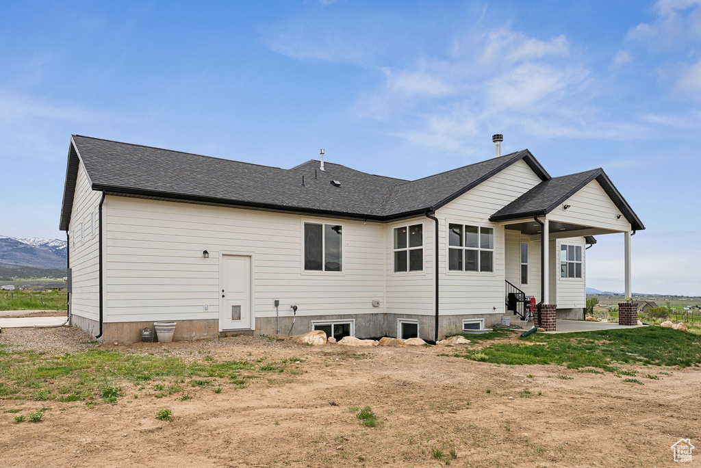 Back of property with a patio area, entry steps, and roof with shingles