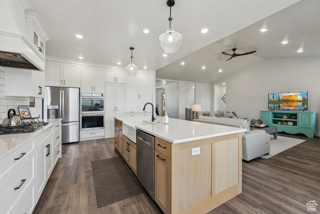 Kitchen featuring a sink, stainless steel appliances, open floor plan, decorative backsplash, and ceiling fan