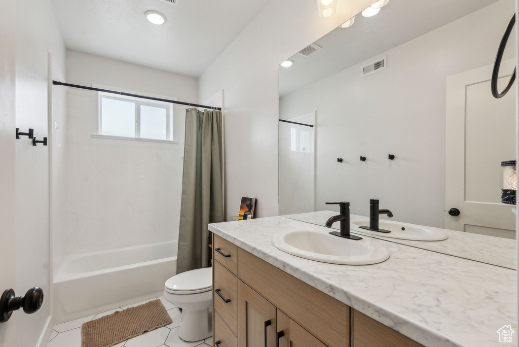 Bathroom with tile patterned floors, toilet, shower / tub combo, and vanity