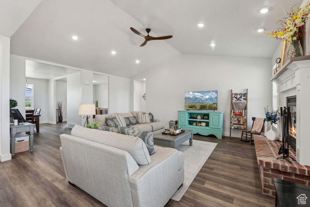 Living area featuring a ceiling fan, recessed lighting, a brick fireplace, dark wood-type flooring, and vaulted ceiling