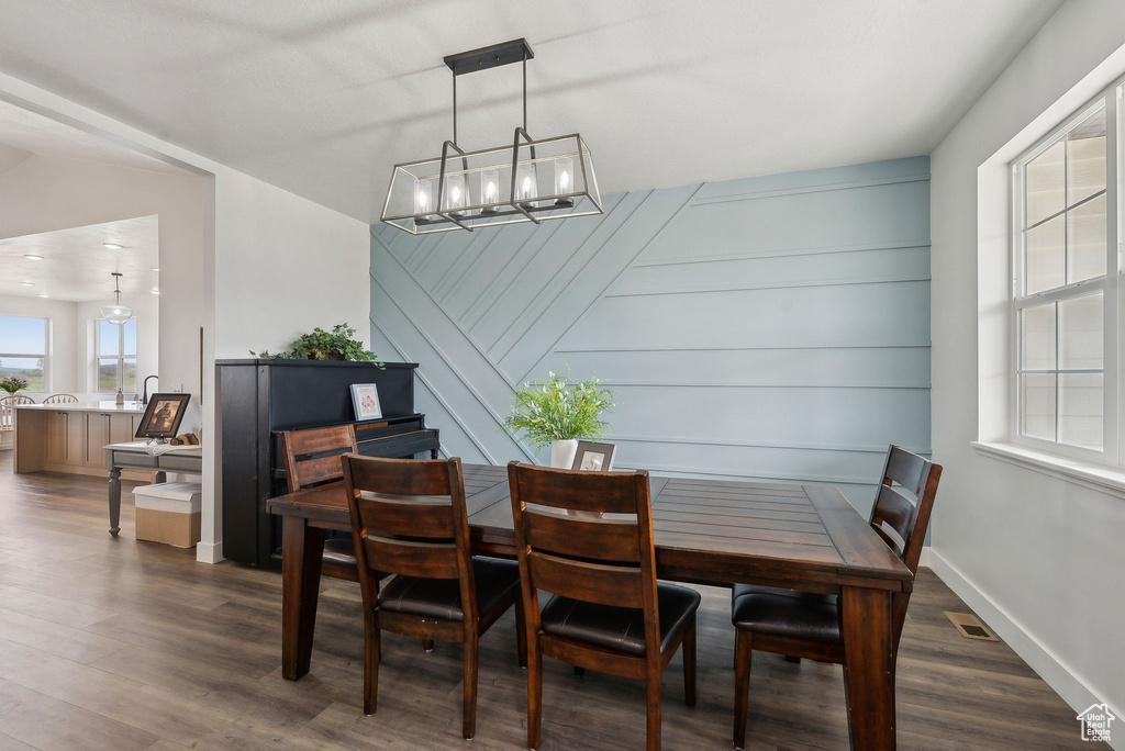 Dining room with dark wood-style floors, a chandelier, and baseboards