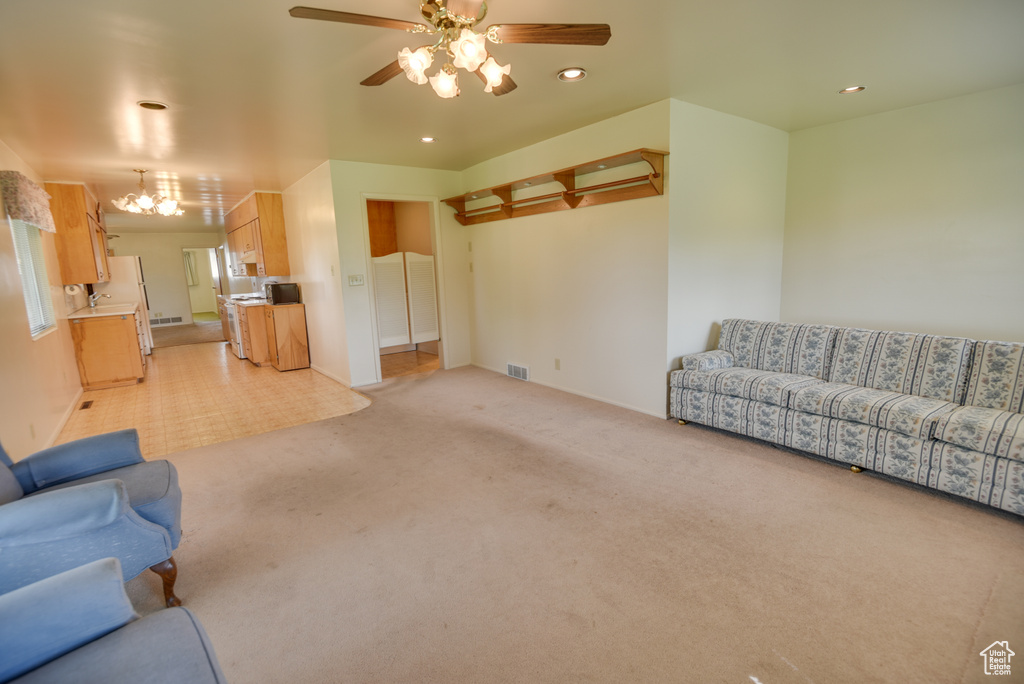 Unfurnished living room featuring light colored carpet, a ceiling fan, recessed lighting, and a chandelier