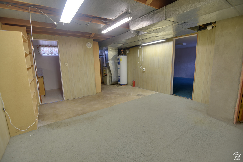Below grade area featuring water heater, heating unit, and carpet