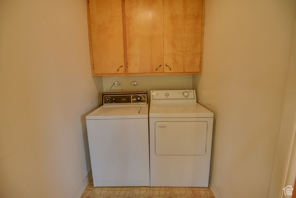 Washroom featuring independent washer and dryer, cabinet space, and baseboards