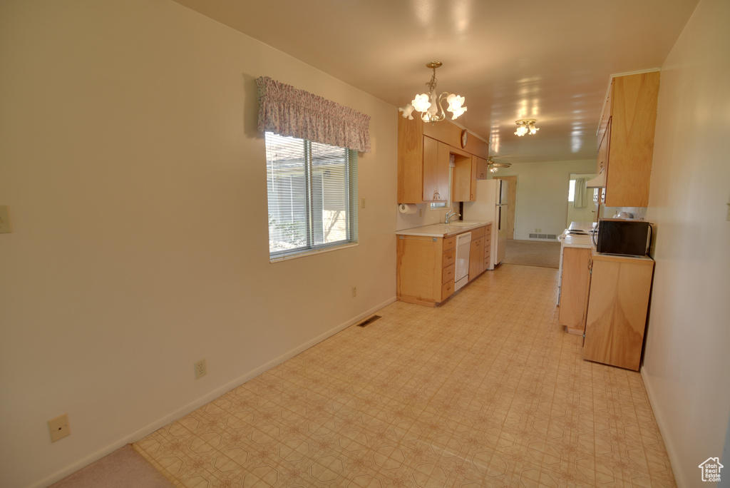 Kitchen with white appliances, light countertops, a chandelier, baseboards, and light floors