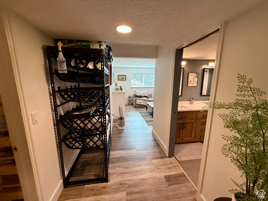Hall featuring a textured ceiling, light wood-style floors, recessed lighting, and baseboards