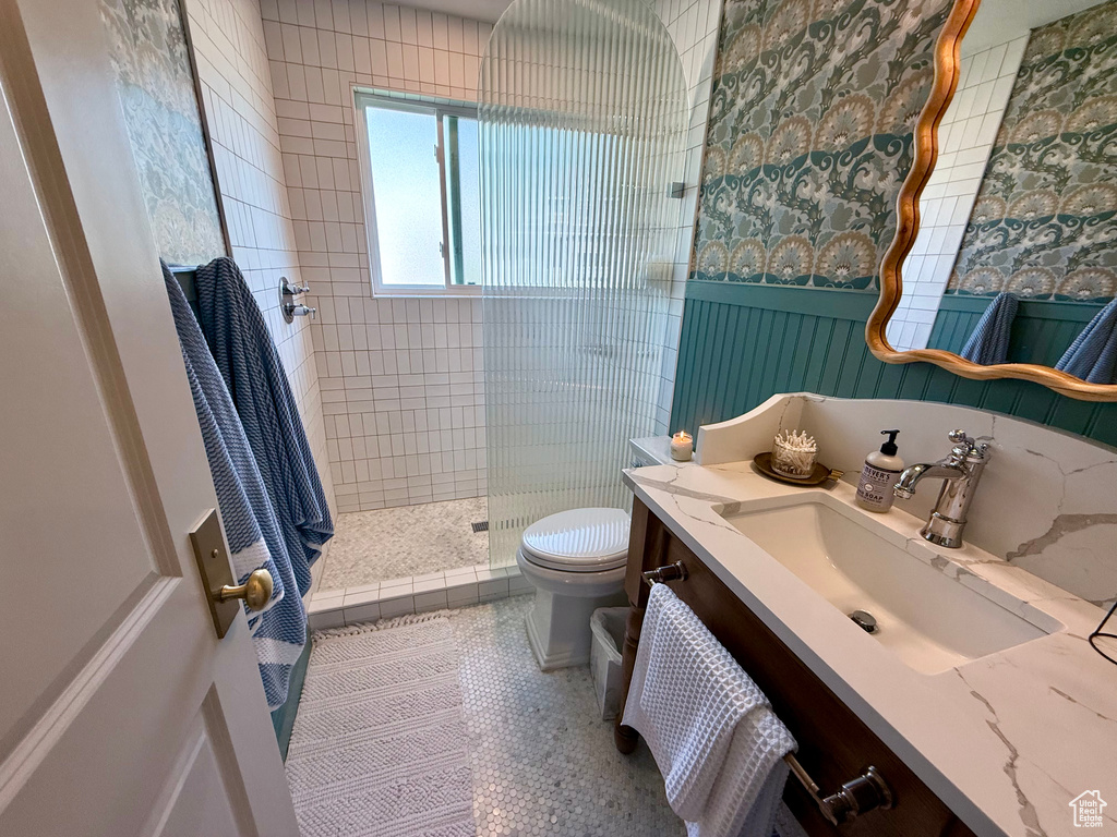 Full bathroom with toilet, vanity, and a tile shower