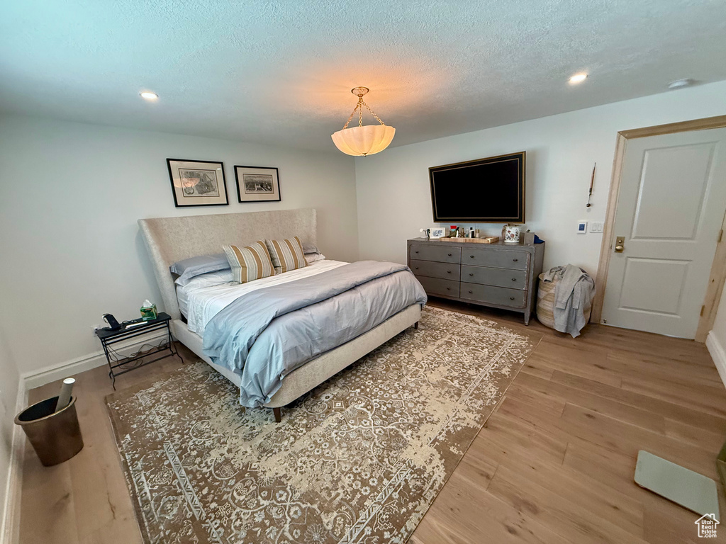 Bedroom featuring light wood-type flooring, recessed lighting, a textured ceiling, and baseboards