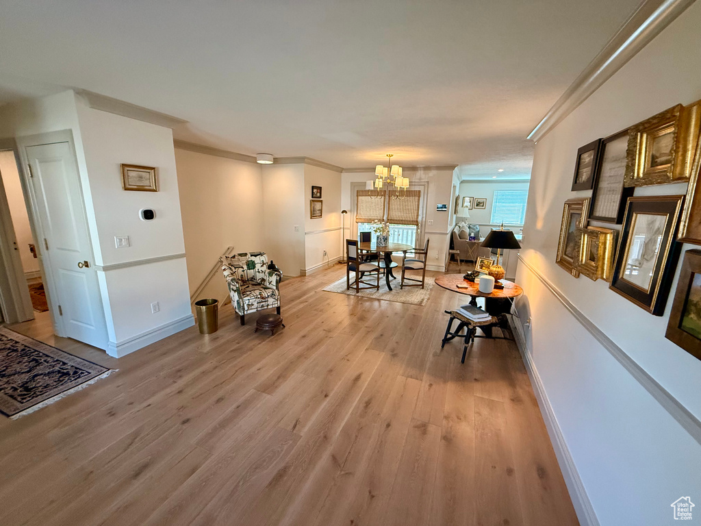 Dining space with light wood-type flooring, a chandelier, ornamental molding, and baseboards